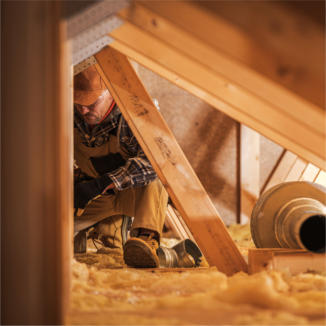 isolation-des-combles Un ouvrier installe de l'isolant dans les combles