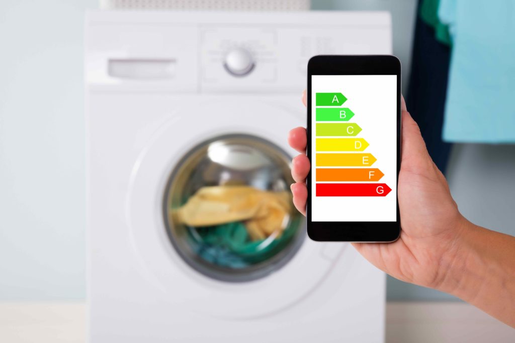 Un smartphone affiche une étiquette énergie correspondant à un lave linge en fond